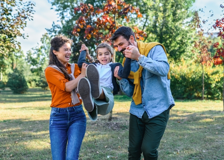 happy family swinging a child by hands